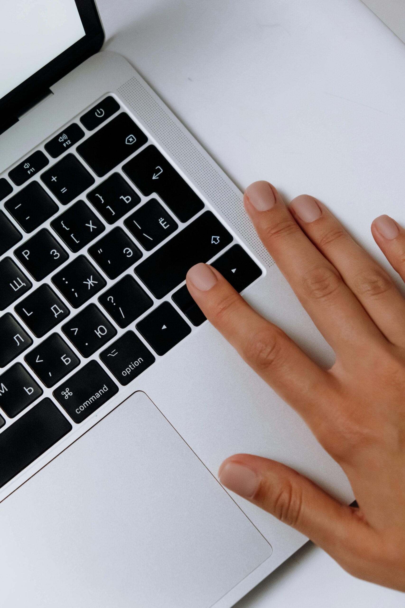 A close-up of a hand touching a laptop keyboard with Cyrillic letters, showcasing technology and work.